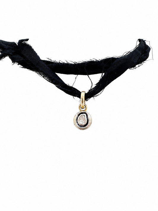 A black frayed fabric choker necklace with a small gold pendant featuring a clear teardrop gemstone, shown against a plain white background.